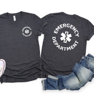 May include: Two dark heather grey t-shirts with a white circle graphic on the front and back. The graphic features a white medical symbol with a snake and a staff, and the text "Emergency Department".