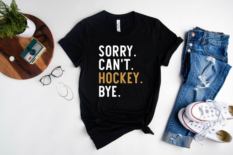 May include: Black t-shirt with the text "SORRY. CAN'T. HOCKEY. BYE." in white and gold lettering.