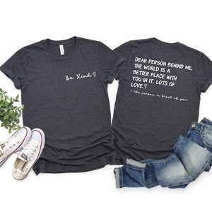 May include: Two heather grey t-shirts with a matching design. The front of one shirt says "Be Kind" with a heart symbol. The back of the other shirt says "Dear person behind me, the world is a better place with you in it. Lots of love. - the person in front of you".