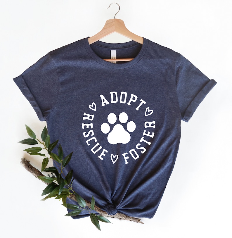 May include: A dark blue t-shirt with a white paw print and the text "Adopt, Rescue, Foster" in a circle around the paw print.