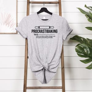 May include: Grey t-shirt with a black graphic that says "PROCRASTIBAKING" and defines it as a verb: "when you have a million things to do but ignore everything and bake."