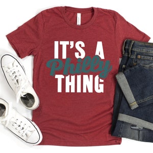 May include: Red t-shirt with the text "It's a Philly Thing" in white and teal lettering.