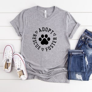 May include: Gray t-shirt with a black paw print and the text "Rescue Adopt Foster" in a circle.