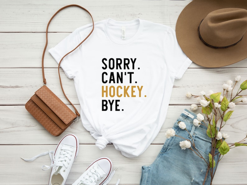 May include: White t-shirt with black text that reads "Sorry. Can't. Hockey. Bye."