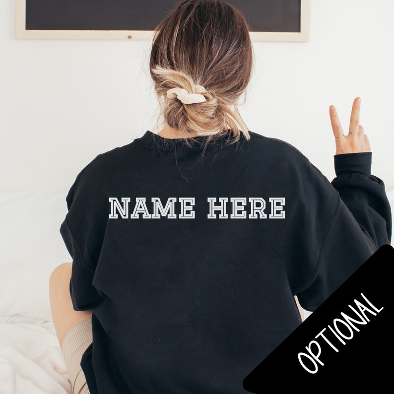 Pode incluir: Camisola de moletom preta com texto branco que diz "NAME HERE" nas costas.