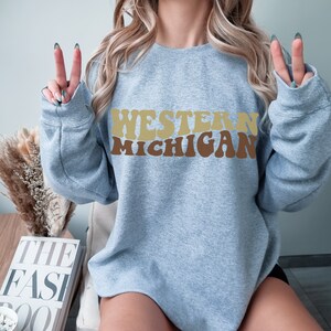 May include: A light blue sweatshirt with the text "WESTERN MICHIGAN" in brown, yellow, and orange retro-style lettering.
