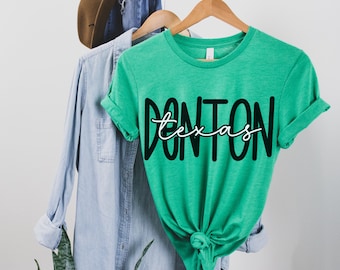 Pode incluir: Uma camiseta verde com o texto "Don't on Texas" em letras pretas e brancas.
