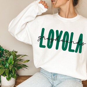 Pode incluir: Camisola branca com texto verde que diz "LOYOLA greyhounds".