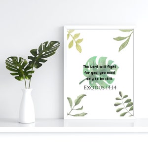 Op de afbeelding: Witte ingelijste print met een groen aquarel bladontwerp en de tekst "The Lord will fight for you; you need only to be still. EXODUS 14:14"