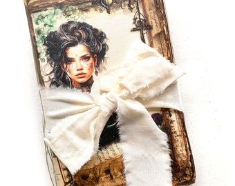 Op de afbeelding: Een vintage-stijl dagboek met een portret van een vrouw op de omslag, vastgebonden met een crèmekleurig lint. De pagina's van het dagboek hebben een verweerde, verouderde uitstraling, met decoratieve elementen en tekst. De omslag toont een vrouw met donker haar.