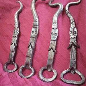 May include: Four silver bottle openers with a unique design. Each opener has a face with a beard and a star design on the handle.