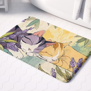 May include: A bath mat featuring a watercolour design of two cats napping in a field of lavender. The cats are a grey tabby and an orange tabby. The background is a soft yellow with green leaves and purple lavender flowers.