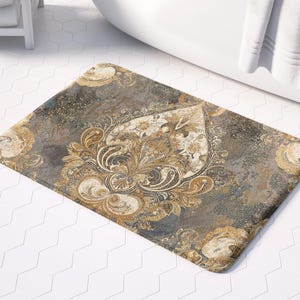 May include: A grey and gold bath mat with a paisley pattern. The mat has a textured surface and is designed to absorb water.