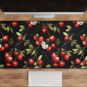 May include: Black desk mat with a repeating pattern of red cherries and white flowers on green stems.