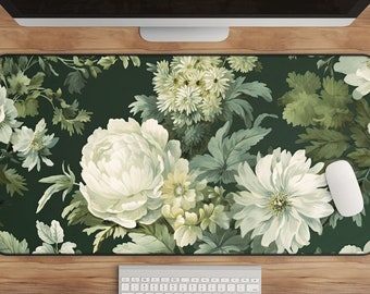 May include: A green floral patterned desk mat with white flowers and leaves. The mat is on a wooden surface with a white keyboard and a white computer mouse.