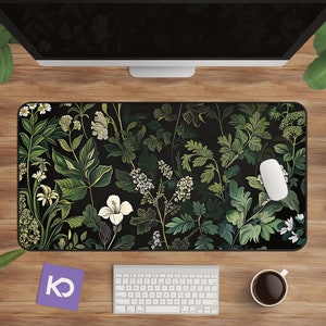 May include: A black mouse pad with a green and white floral design. The design features leaves, flowers, and stems in shades of green and white on a black background.