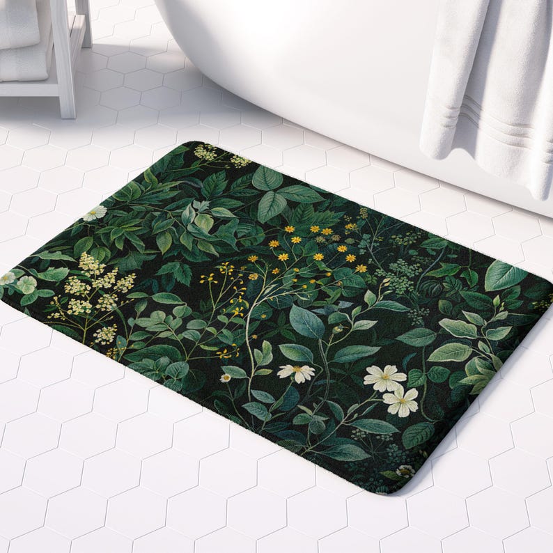 May include: A rectangular bath mat featuring a dark background with a botanical design. The mat showcases a variety of green leaves, white flowers, and yellow accents. The mat is placed on a white tile floor near a white bathtub.