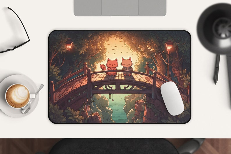 Pu&ograve; includere: Un tappetino per mouse con un'illustrazione fantasiosa di due gatti seduti su un ponte di legno sopra un ruscello. Il ponte &egrave; circondato da alberi verdi lussureggianti e lo sfondo &egrave; un dolce tramonto.