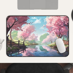 May include: A mouse pad with a scenic image of a river flowing through a forest with pink cherry blossom trees. The river reflects the trees and sky.