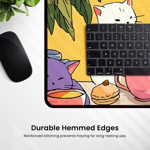 Peut inclure: Tapis de souris rectangulaire avec une illustration de chats, de nourriture et de boissons. Un clavier noir est pos&eacute; sur le tapis. Le tapis de souris a des bords ourl&eacute;s durables. Le texte "Durable Hemmed Edges" est imprim&eacute; en bas.