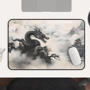 May include: A black and white mousepad with a dragon flying over a mountain range and a pagoda in the background. The dragon is in a cloud of smoke and the mountain range is covered in fog.