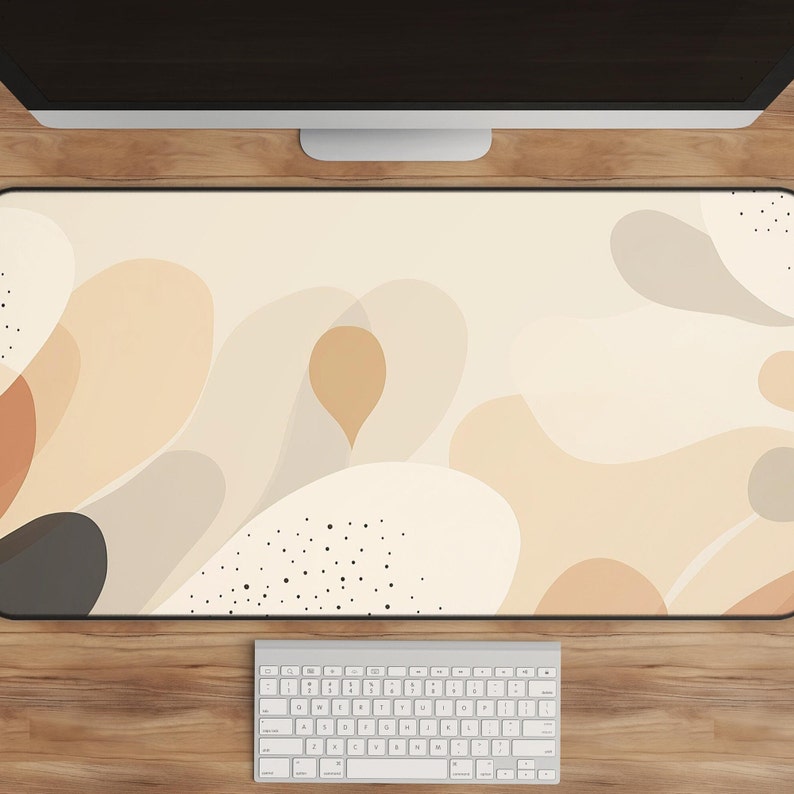 May include: A beige and brown abstract design desk mat with black dots. The mat is on a wooden desk with a white keyboard.
