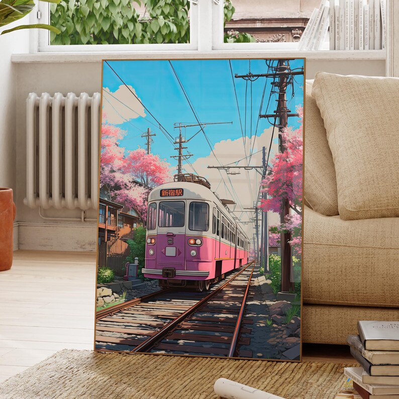 May include: A pink and white train with the text "新前橋駅" on the front, traveling on a track through a lush green forest with cherry blossoms in bloom. The sky is blue with white clouds.