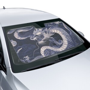 May include: A car windshield sunshade featuring a detailed illustration of a white and blue dragon with a black background. The dragon is curled up in a defensive position with its head facing the viewer.