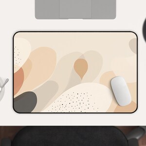 May include: A beige and brown abstract design mouse pad with a white mouse on top. The mouse pad has a black border and a subtle pattern of black dots.