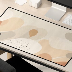 May include: A beige and brown abstract design mousepad with black dots and a black border.