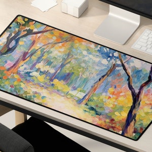May include: A colorful abstract painting of a forest scene with trees and foliage in shades of blue, green, yellow, and pink. The painting is on a black background and is framed with a black border.