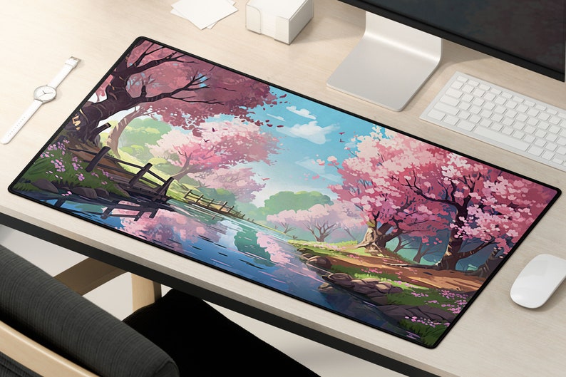 May include: A black mousepad with a colorful illustration of a Japanese garden scene. The scene features a winding river, a wooden bridge, and pink cherry blossom trees.