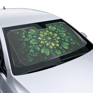 May include: Green car sunshade with a floral design featuring a large green flower with a yellow centre surrounded by green leaves.