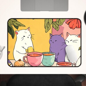 Peut inclure: Tapis de souris rectangulaire avec une illustration de trois chats autour d'une table avec des tasses de th&eacute;. Les chats sont blancs et violets, avec un fond jaune et des feuilles vertes. Une souris blanche est &agrave; droite.