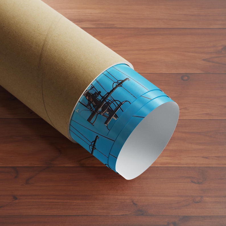 May include: A rolled up poster tube with a blue and white design featuring a silhouette of a person working on a power line. The tube is made of cardboard and has a brown exterior.
