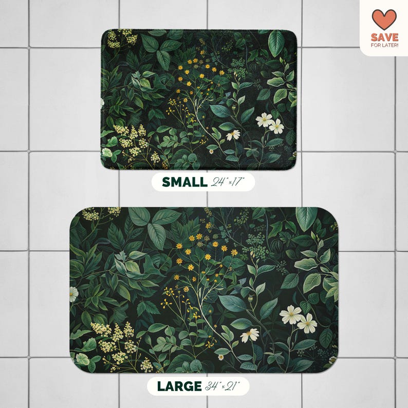 May include: Two rectangular bath mats with a dark green botanical design featuring leaves, white flowers, and yellow accents. The smaller mat is 24" x 17", and the larger mat is 34" x 21". The mats have rounded corners and are placed on a tiled surface.