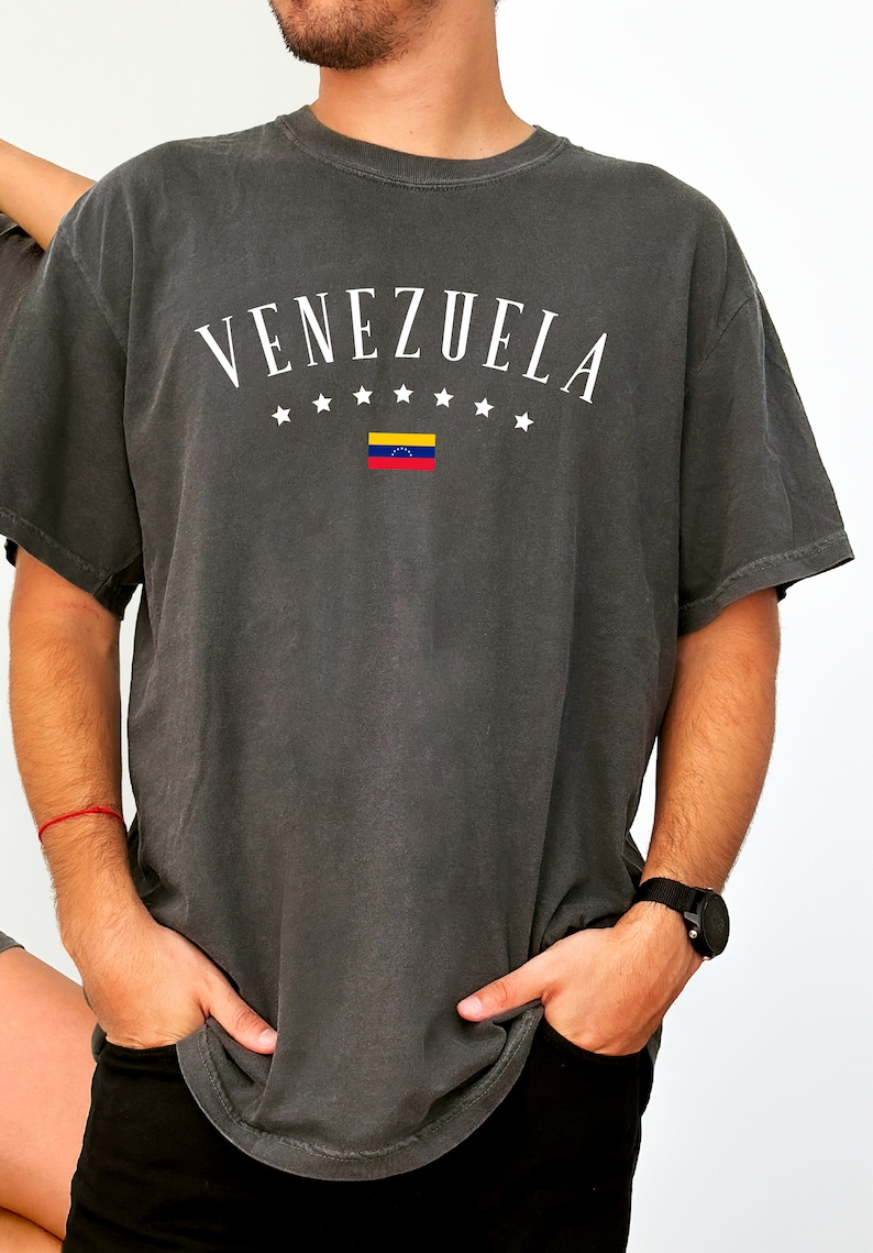 May include: A dark gray t-shirt with the word "VENEZUELA" printed in white with a small Venezuelan flag and stars.