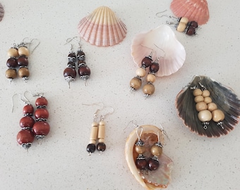 May include: Assortment of wooden bead earrings in various colors and styles. The earrings are displayed on seashells.