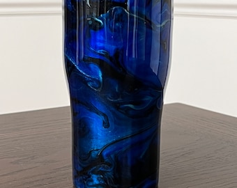 Peut inclure: Un gobelet en acier inoxydable marbré bleu et noir avec un couvercle argenté. Le gobelet présente un motif tourbillonnant de peinture bleue et noire.