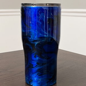 May include: A blue and black marbled stainless steel tumbler with a silver lid.
