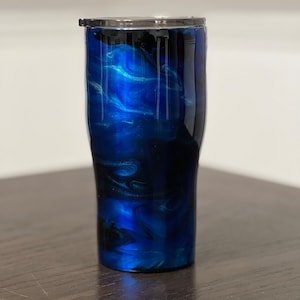 May include: A blue and black stainless steel tumbler with a marbled design. The tumbler has a lid.