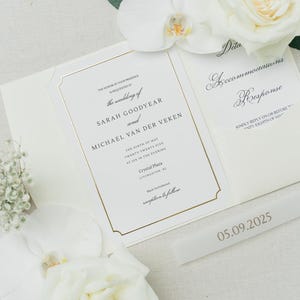 May include: A white wedding invitation suite with gold foil borders and black serif typography. The text reads: The honor of your presence is requested at the wedding of Sarah Goodyear and Michael Van Der Veken, May 9, 2025, at Crystal Plaza.