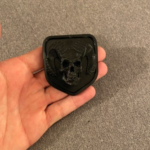 Puede incluir: Un cráneo negro impreso en 3D con cuernos, en forma de escudo.