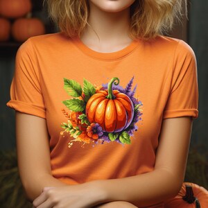 May include: Orange t-shirt with a colorful illustration of a pumpkin with green leaves and purple flowers.