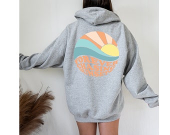 May include: Gray hooded sweatshirt with a graphic of a sun setting over a wave. The graphic is in shades of orange, yellow, blue, and green. The text "FOREVER CHASING SUNSET" is written in a circular pattern around the graphic.