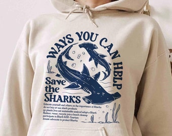 May include: A beige hoodie with a blue graphic of hammerhead sharks and the text "Ways You Can Help Save the Sharks". The graphic also includes text about how to help protect sharks.