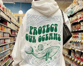 May include: White hoodie with a green and blue graphic of a whale swimming in a galaxy with the text "Protect Our Oceans".