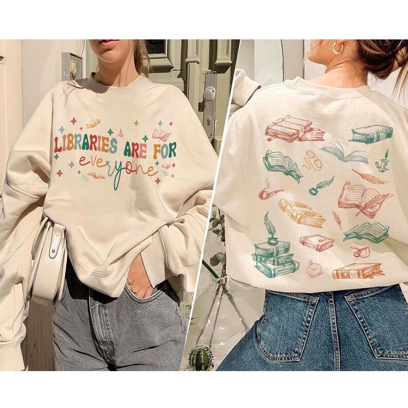 May include: A cream-colored sweatshirt with the text "LIBRARIES ARE FOR everyone" in colorful letters and stars. The back of the sweatshirt has a pattern of books, pens, and feathers.