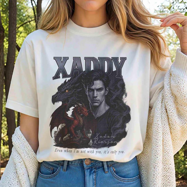 Puede incluir: Camiseta color crema con un dise&ntilde;o gr&aacute;fico. El dise&ntilde;o presenta la palabra "XADDY" en gris, un retrato de un hombre, dos dragones y el texto "Kaden Roarson" y "Even when I'm not with you, it's only you."