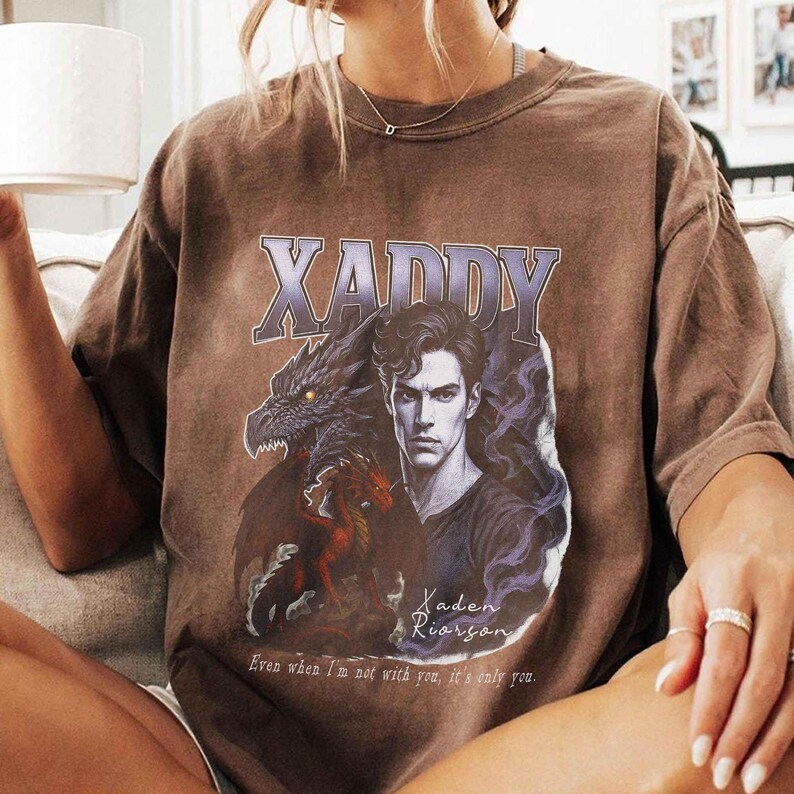 Puede incluir: Camiseta marr&oacute;n con un dise&ntilde;o gr&aacute;fico. El dise&ntilde;o presenta la palabra "XADDY", un retrato de un hombre, un drag&oacute;n y el texto "Kaden Riorgson" y "Even when I'm not with you, it's only you."